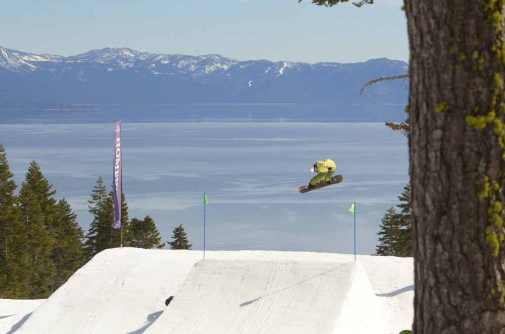 snowboarder catching air with a lake in the background