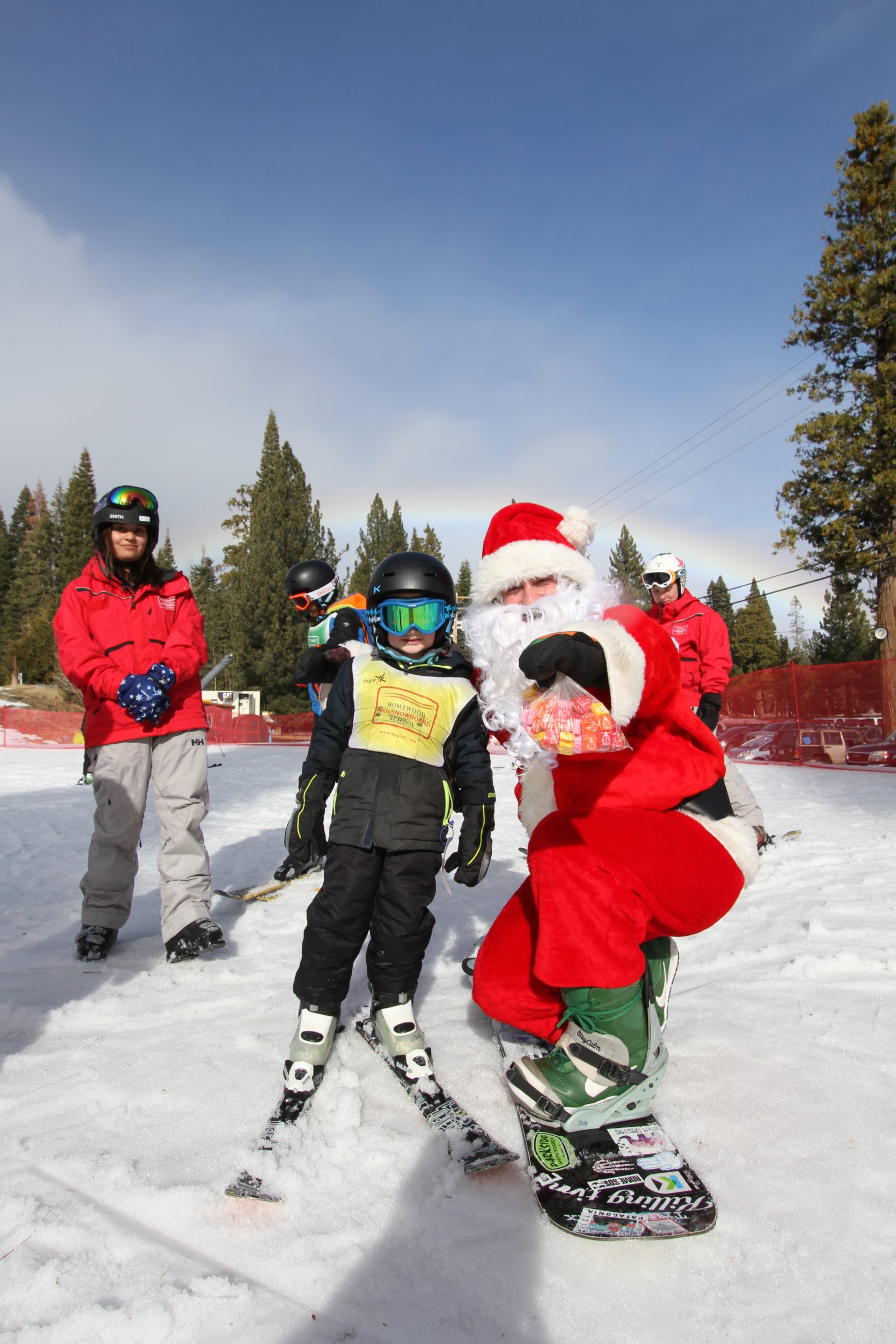 Santa with a child learning to ski with Santa